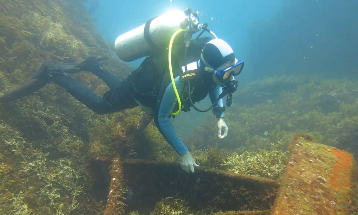 A diver inspects a metal structure on seafloor