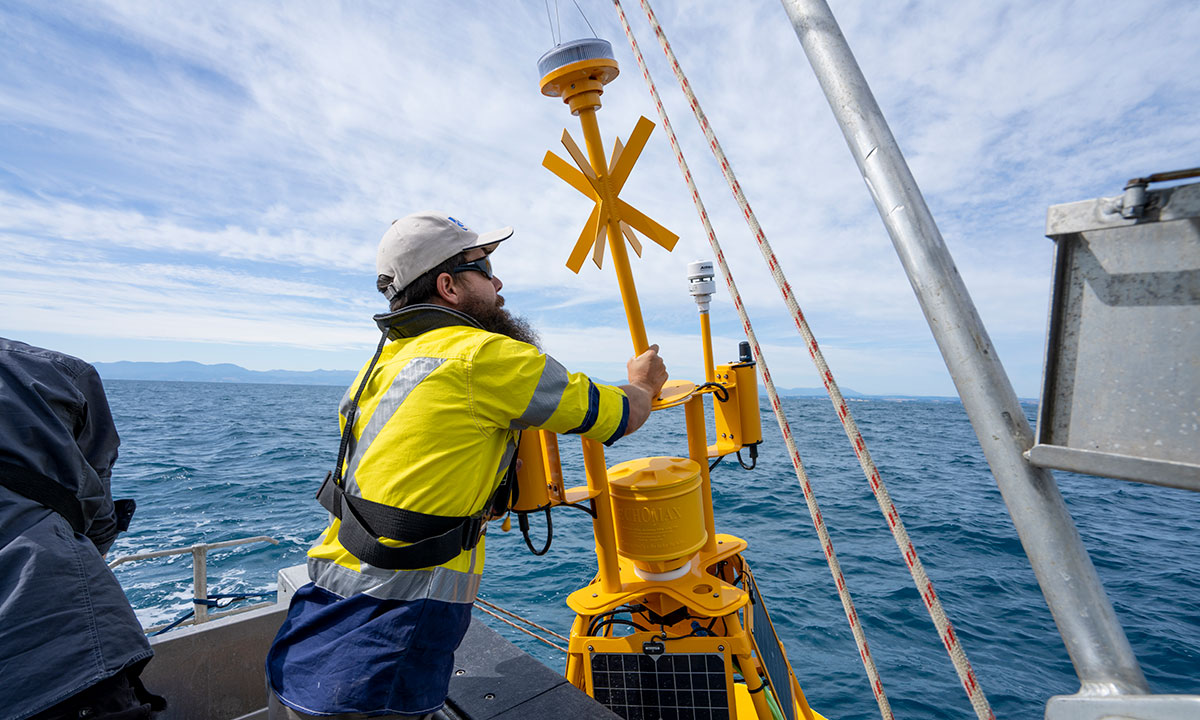 Man deploys coastal monitoring buoy from boat