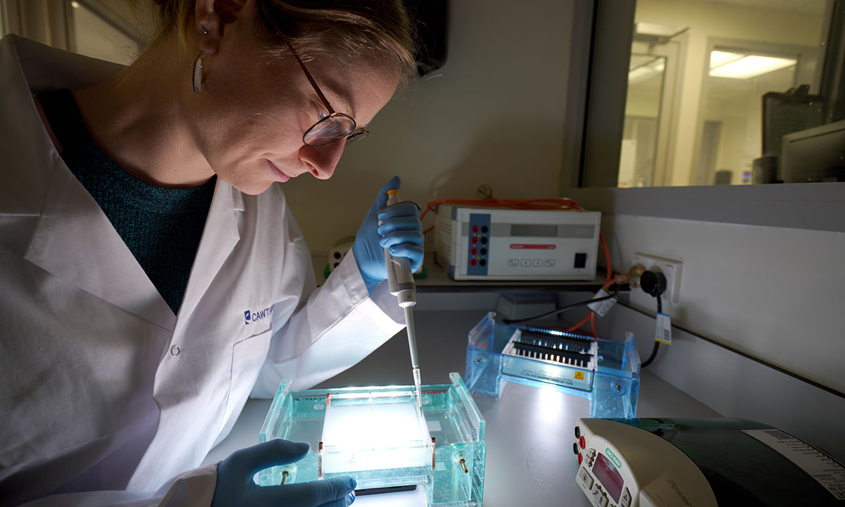 Laboratory technician watches sample being analysed in machine